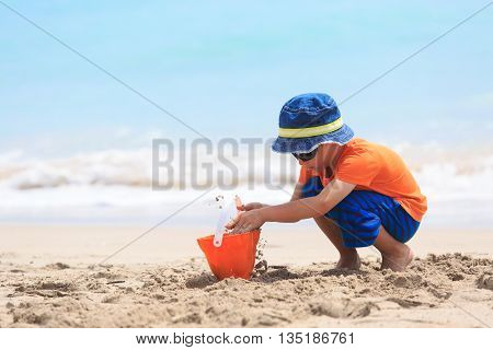 little boy play with sand on summer beach