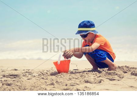 little boy play with sand on summer beach