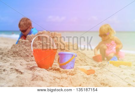 kids play with sand on summer beach, family vacation