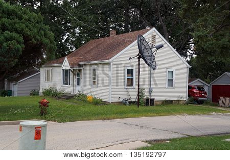 SHOREWOOD, ILLINOIS / UNITED STATES - AUGUST 30, 2015: A small Cape Cod style home, with a large satellite dish, in Shorewood, Illinois.