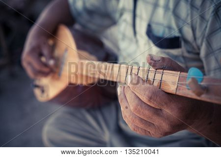 Close up shot of a man playing a Tatar instrument called 