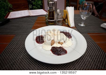papanasi is traditional romanian dessert fried or boiled and served with sour cream and cherry or blueberry jam