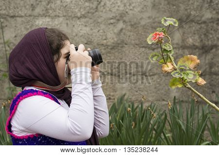 Young Little Girl Is Taking Photograph by an Analogue Camera Strapped on Her Neck in Flower Garden