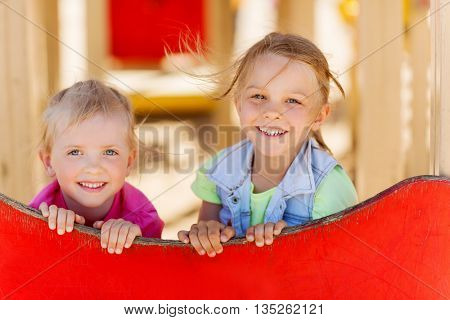 summer, childhood, leisure, friendship and people concept - happy kids on children playground climbing frame