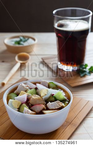 A cup of russian cold soup okroshka and a glass of bread kvass