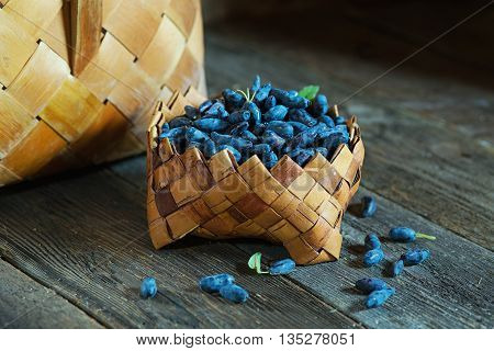 Honeysuckle berries in a basket on a old wooden surface