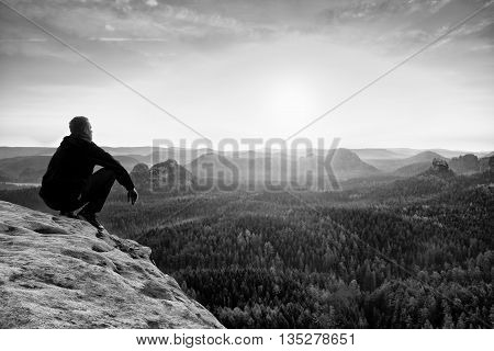 Adult In Black Trousers, Jacket Sit On Cliff's Edge