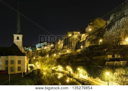 Sykline of Louxemburg City at night with a view over the Bockfelsen and reflections of the streetlights in the river Alzette.