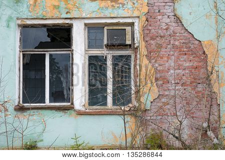 Old evicted and destroyed house with a ruined wall and broken window