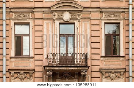 Three windows in a row nd balcony on facade of urban apartment building front view St. Petersburg Russia