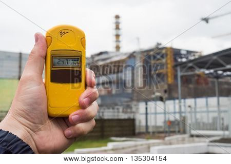 radiometer in hand with fourth Chernobyl reactor on the background