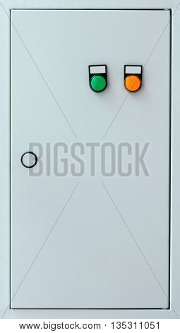 Grey colored door of the electric cabinet with the green and orange buttons.
