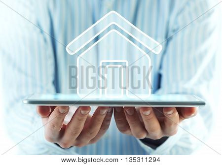 Businessman holding in hands tablet pc and home icon on screen