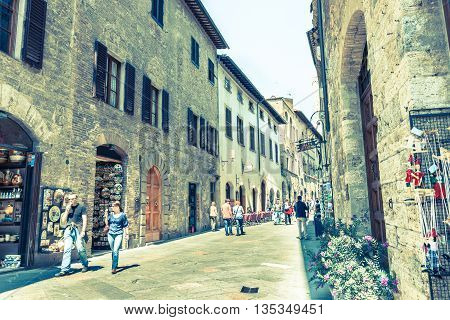 San Gimignano, Italy - April 18, 2011; Old image faded colors effect of tourists in in narrow street Italian Tuscan walled city of San Gimignano