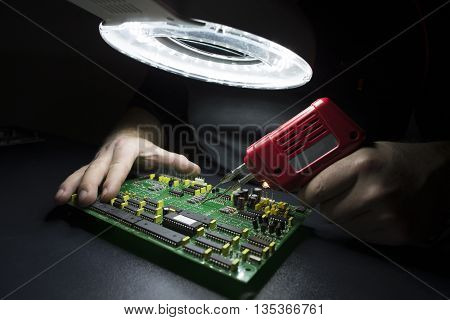 Man hands fixing computer motherboard on the black workbench
