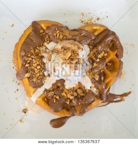 Waffle with a shape of a heart having a ball of stracciatella ice cream on top of it.