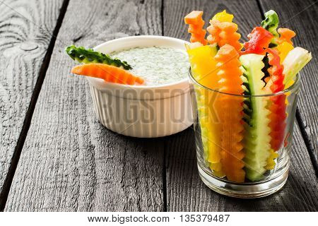 Colorful slices of raw vegetables in glasses (carrots celery cucumber sweet pepper) and yogurt sauce. The concept of diet healthy and vegetarian food. Selective focus