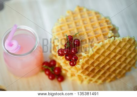 Belgian waffles with fresh berries on cutting board on background of rustic. grapefruit juice. pink cocktail with a straw.