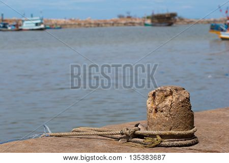 A mooring on a dock in a port keeps an old fishing trawler tethered in place.