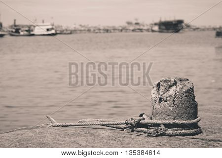 A mooring on a dock in a port keeps an old fishing trawler tethered in place.