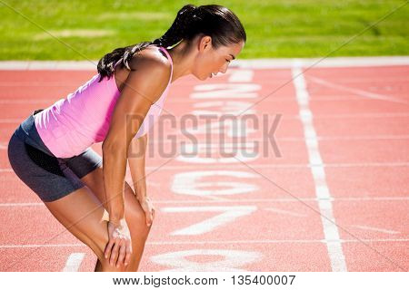 Profile view of breathless sportswoman against close up of the track starting point