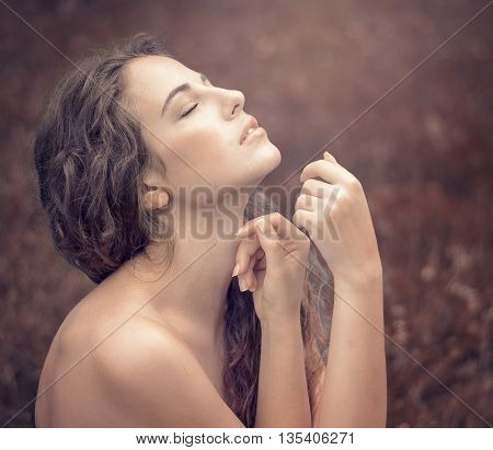 beautiful young woman in a long white dress with long wavy hair lying on the large roots of a tree with eyes closed. Fairy tale. Dream