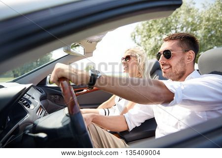 road trip, travel, dating, couple and people concept - happy man and woman driving in cabriolet car outdoors
