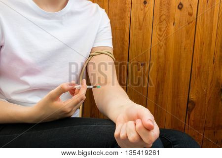Young Woman Bandaged Arm And Injects Drugs
