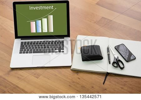wooden desk with computer and notebook - chart Investment