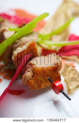 Closeup of a skewer of pork jowls.
