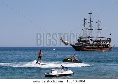 CAMYUVA KEMER TURKEY - JULY 16 2015: On the coast of Turkey along with the traditional personal watercraft are becoming popular flyboard and yachting stylized pirate schooner