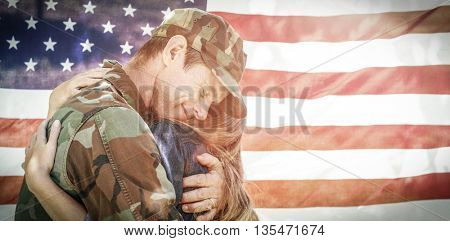 American soldier embracing his partner in front of american flag while reuniting
