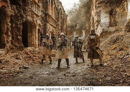 Nuclear post-apocalypse. Survivors in tatters and gas mask on the ruins of the destroyed city