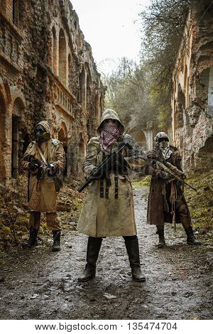 Nuclear post-apocalypse. Survivors in tatters and gas mask on the ruins of the destroyed city