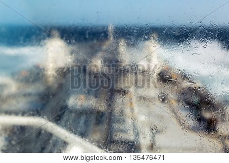 Sea drops on the ships window with blurred deck background.
