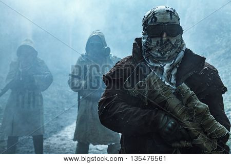 Nuclear post-apocalypse. Survivors in tatters and gas mask on the ruins of the destroyed city
