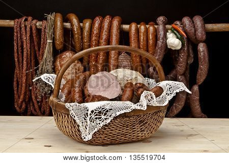 basket meats, on woden table, hanging sausages in the background