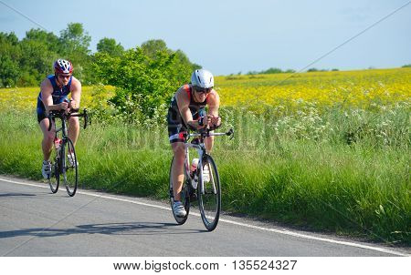 Grafham, Cambridgeshire, England - May 22, 2016:  Triathletes on road cycling stage of triathlon fields and trees in background.