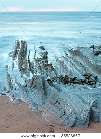 Twilight Ocean Coast With Ribbed Stratiform Rock.