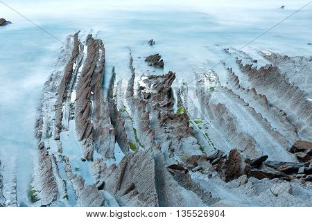 Twilight Ocean Coast With Ribbed Stratiform Rock.