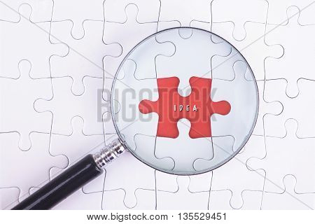 Business Concept - Magnifier Glass on white puzze with IDEA Word