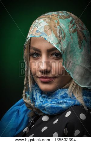 Beautiful young blonde woman against dark green background