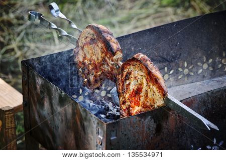 Cooking meat on the grill. Large chunks of pork threaded on skewers.