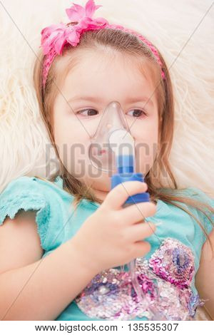 Little girl using an inhaler indoors. nebulizer