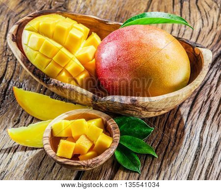 Mango fruit and mango cubes on the wooden table.