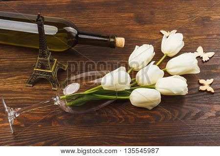 Wineglass with bouquet of white tulips on the wooden background