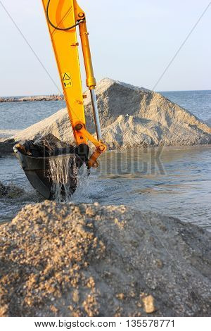 excavator loading dumper truck with sand at construction site