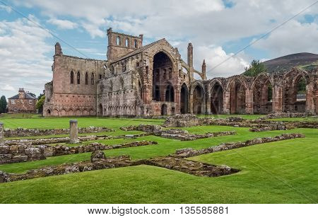The ruins of pink colored Melrose Abbey in the Scottisch Borders region in Scotland