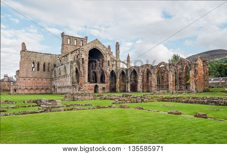 The ruins of pink colored Melrose Abbey in the Scottisch Borders region in Scotland