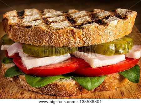Sandwich with chicken, tomatoes and pickles close up